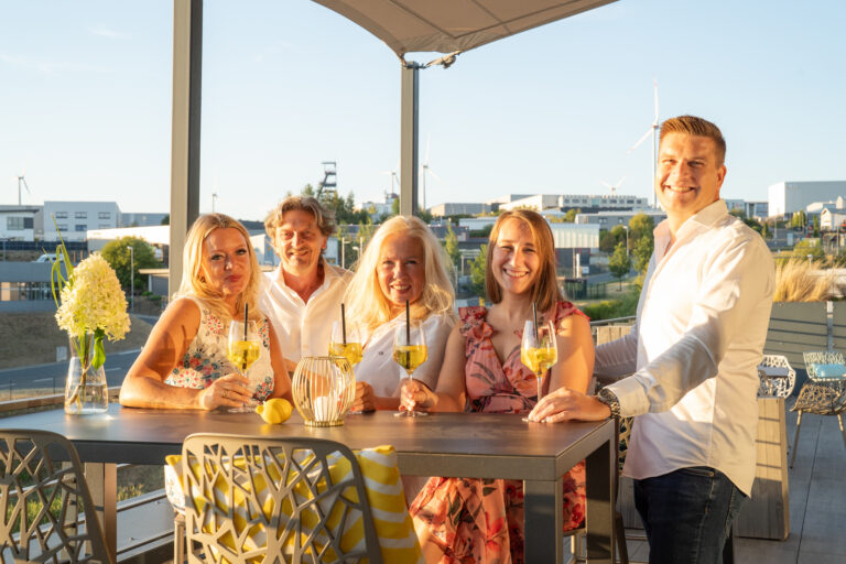 Gäste stoßen bei einer Veranstaltung der Genusswerkstatt auf einer Terrasse an